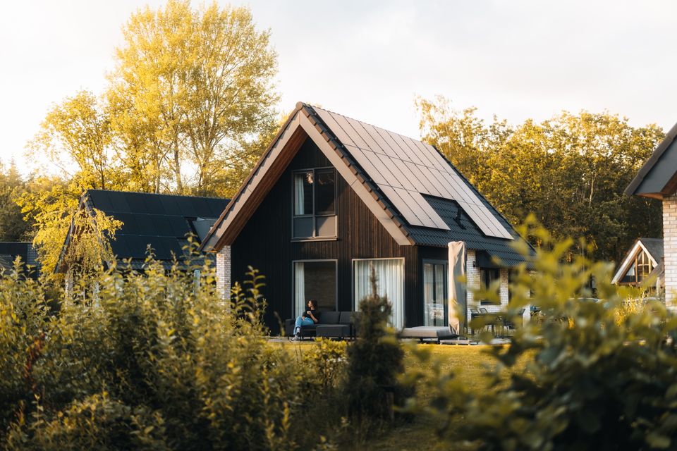 Ein Ferienhaus, umgeben von Bäumen und Sträuchern in einem Ferienpark in Drente.