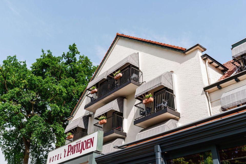 Buitenzijde van Hotel ’t Paviljoen in Rhenen, met balkons en terrassen aan de bosrijke omgeving. Het hotel ligt vlak bij Ouwehands Dierenpark en de natuur van de Utrechtse Heuvelrug.