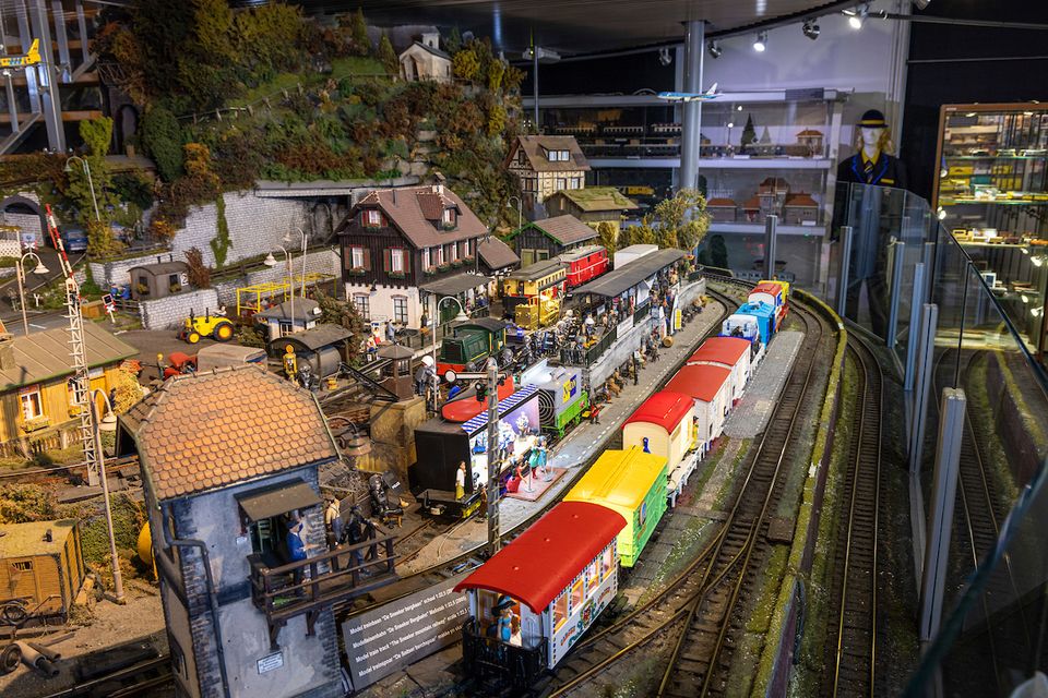 Een foto van een opstelling in het Modelspoor Museum in Sneek met op de voorgrond een kleurrijke trein die rijdt over een spoor.