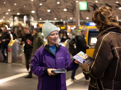 Team van Delft Verlicht die een folder weggeeft aan een bezoeker