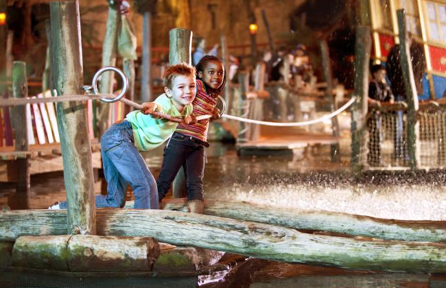 Een jongen een een meisje staan op een vlot en trekken zichzelf met behulp van touw naar de overkant