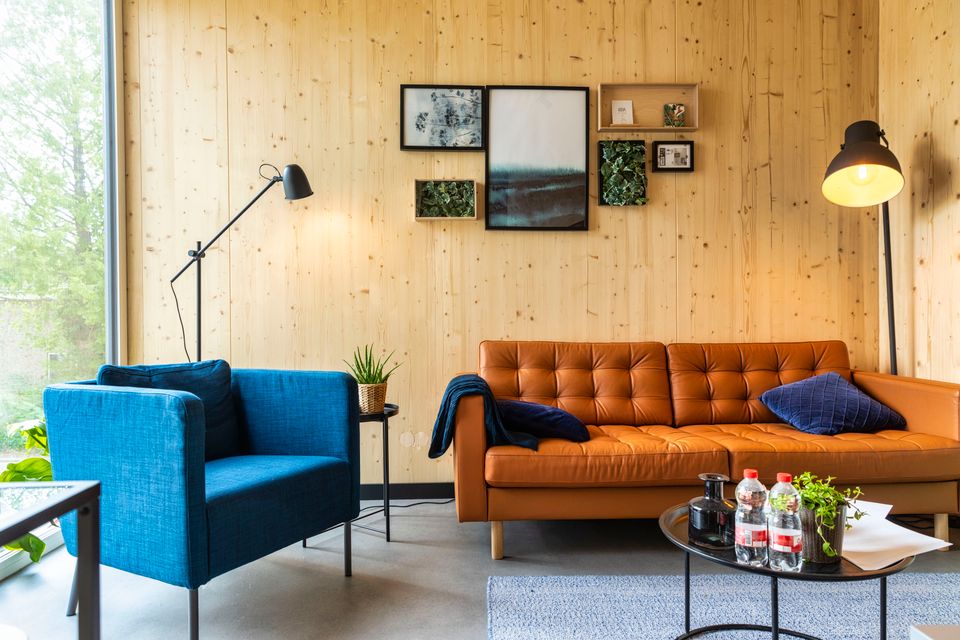 Een woning van een Startblock woning met een bank, stoel en houten muren.