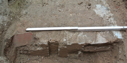 Fundament van Romeins beton aan de Dorpsstraat in Elst. Het vierkante gat geeft de plek aan van een (verdwenen) houten paal; links een fragment van beschilderd pleisterwerk Bron. Verduin 2017.