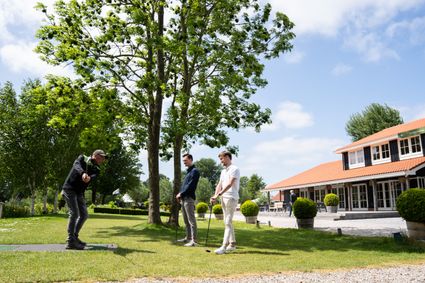 Groepsactiviteit pitch en putt bij Buitenplaats Kameryck in Kamerik, Groene Hart. Bezoekers oefenen met golfclubs op het grasveld naast het restaurant en terras, populair voor teamuitje, bedrijfsuitje en dagje uit in het Utrechtse polderlandschap.