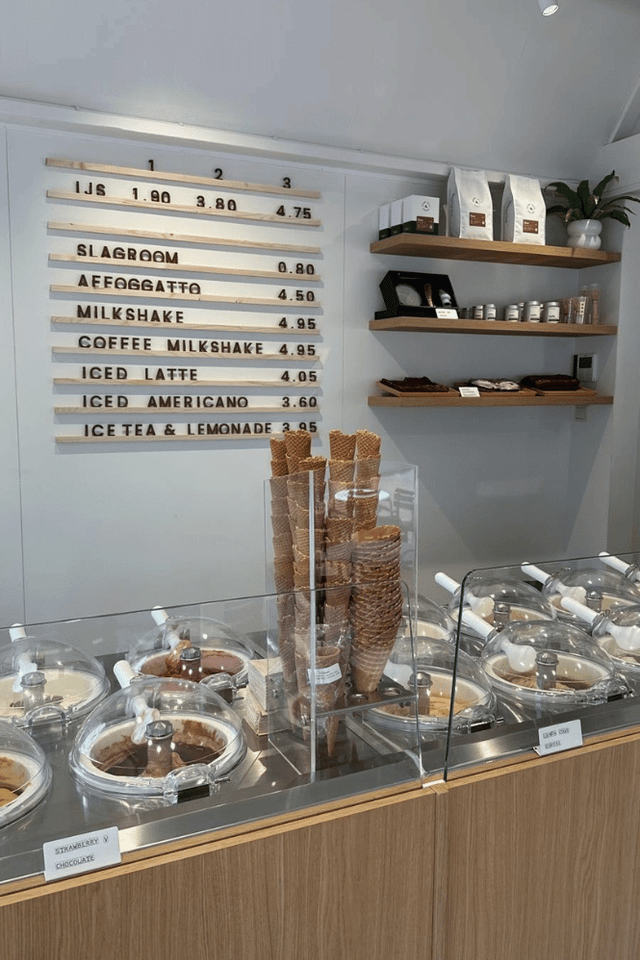 Eine Eisdiele mit Eisbehältern in der Vitrine und einem Stapel Eiswaffeln davor.