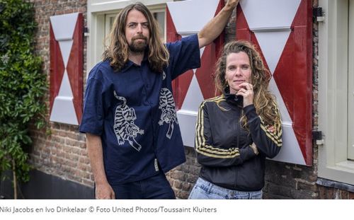 Een man en een vrouw leunend tegen een gebouw