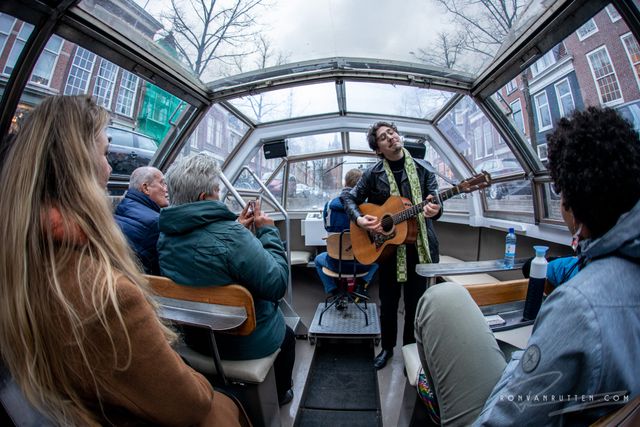 Man op tour boot die gitaar speelt en zingt voor Popronde Delft