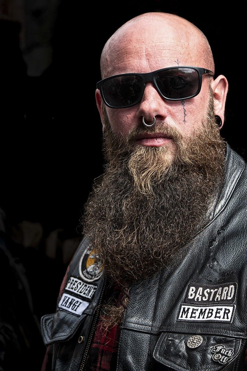 Portretfotografie man met baard en leren jas, close-up portret in Woerden, Groene Hart, krachtige uitstraling met donkere achtergrond en focus op gezichtsuitdrukking en kledingdetails.