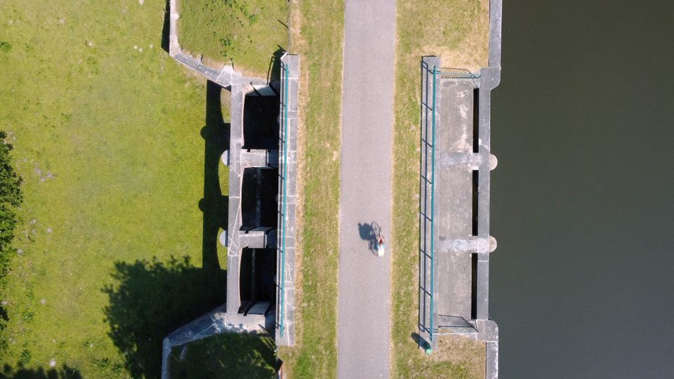 Een sluis van bovenaf gefotografeerd, de deuren zijn zichtbaar. Aan weerszijden is water te zien. Een fietser fietst over de sluis heen.