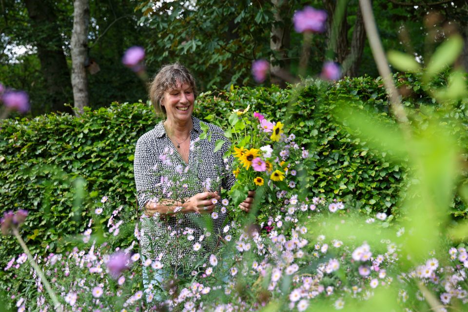 Een vrouw houdt een bosje vers geplukte bloemen vast.