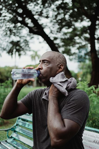 Man drinkt fles water en heeft handdoek in nek voor zweet