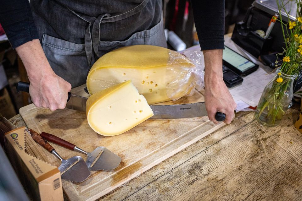 Ambachtelijke kaas wordt aangesneden op een houten plank in een boerderijwinkel in het Groene Hart, vers bereid voor verkoop als streekproduct.