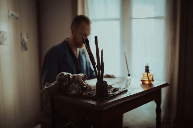 Iemand zit aan en tafeltje te schilderen in de kamer van Van Gogh