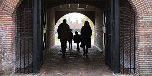 Een gezin loopt door de poort en de hekkenvan het Gevangenismuseum in Veenhuizen. Achter hen zie je het binnenterrein van het Gevangenismuseum liggen.