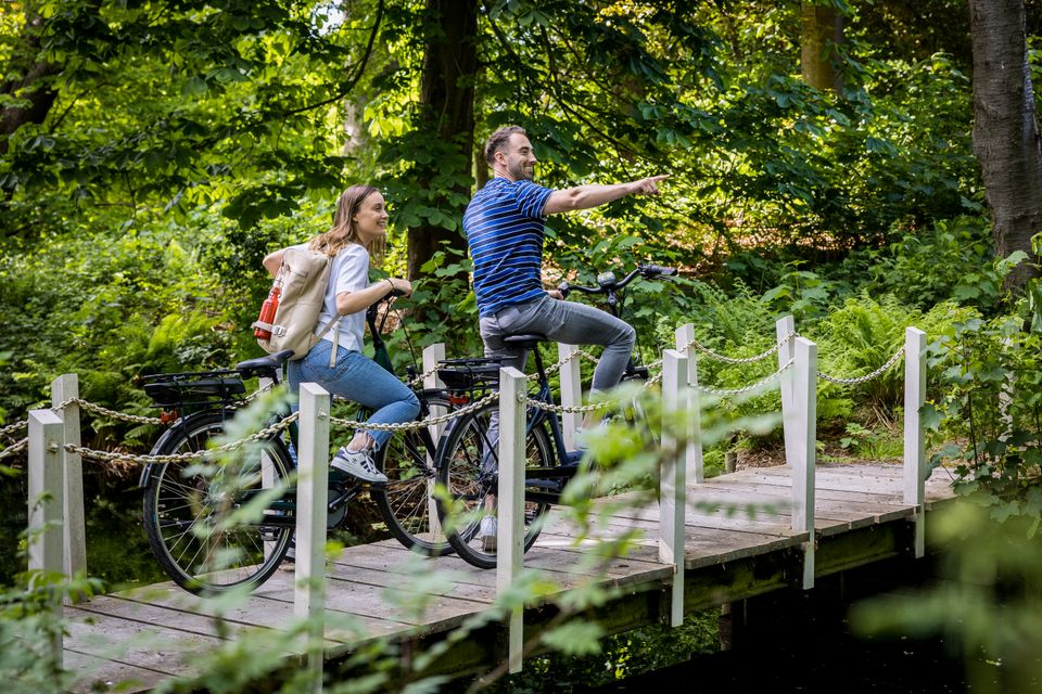 Man en vrouw fietsen over bruggetje