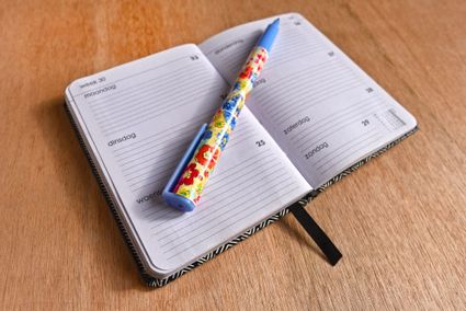 Een agenda ligt opengevouwen op tafel met een pen erop