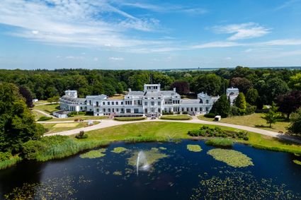 Paleis Soestdijk in combinatie met het water en de fontein. Op de achtergrond zie je het bos van de paleistuin.