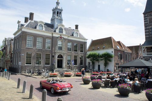 Een auto rijdt op het Damplein in Edam.
