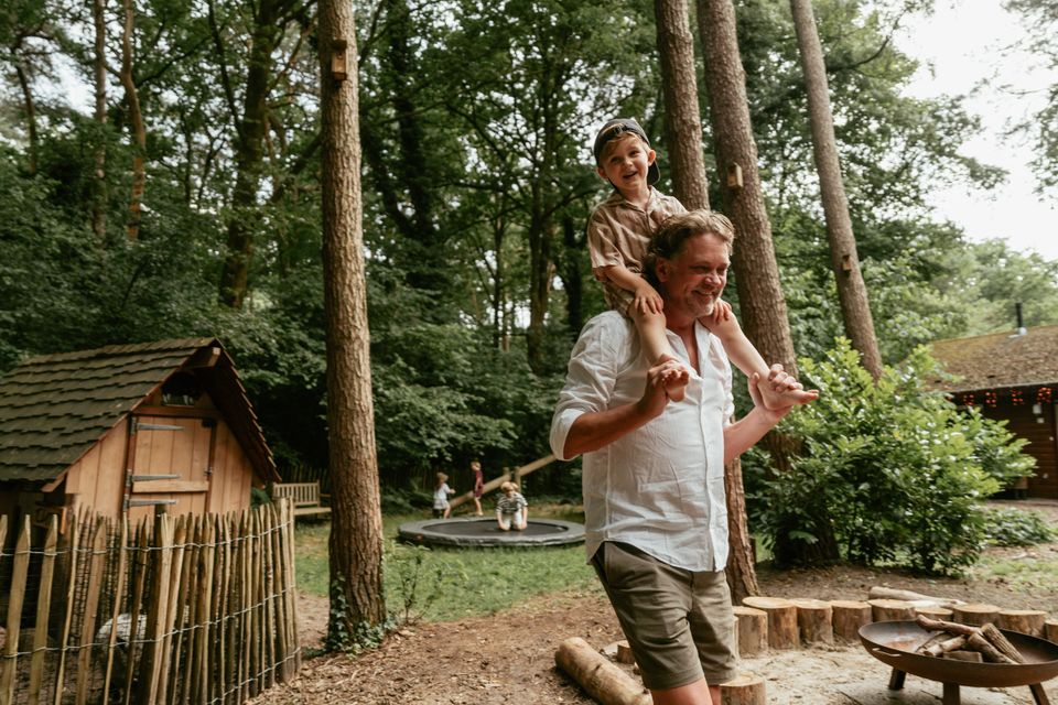 Man met kind op zijn nek die rondloopt op het park