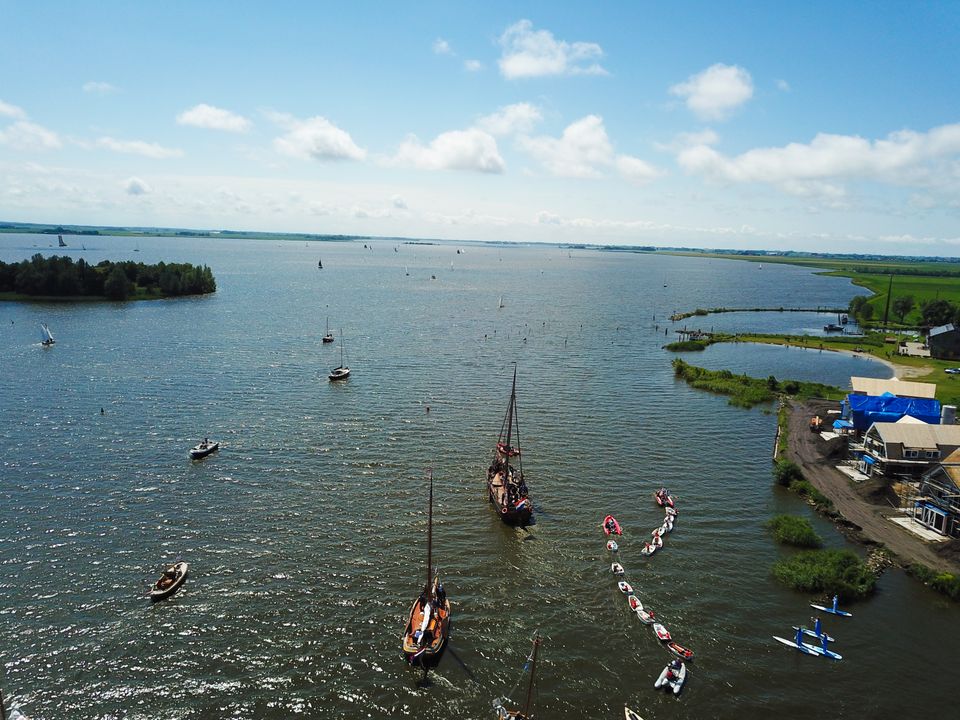 Het skûtsje van Heeg vaart in het water met  zeilboten er om heen.