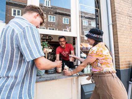 Eigenaar van Koffie en zo geeft een kopje koffie aan een klant
