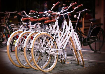 Vier dezelfde witte fietsen staan op een rijtje tegen elkaar aan.