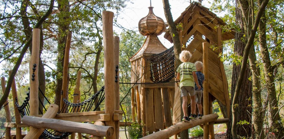 Kinder spielen auf einer hölzernen Kletterburg im Erlebnispark.