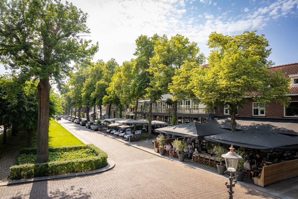 Overzicht van een aantal terrassen vol mensen op De Lind in Oisterwijk en het groene Trouwlaantje