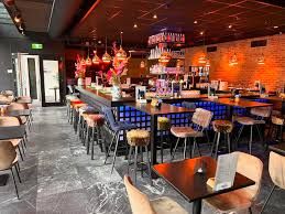 Binnenkant lunchroom met tafels, stoelen en bar.