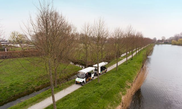 Touwtrein in Oudewater die langs bomen rijdt, over een smal wandelpad, met uitzicht op het water en het groene polderlandschap in het Groene Hart; duurzame rondrit Oudewater.