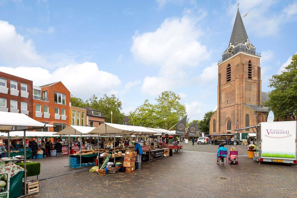 Boerenmarkt Streekmarkt Woerden, Groene Hart, provincie Utrecht, kraam met streekproducten zoals sap, kaas, groente en huisgemaakte lekkernijen onder een markttent met winkelend publiek op het plein.