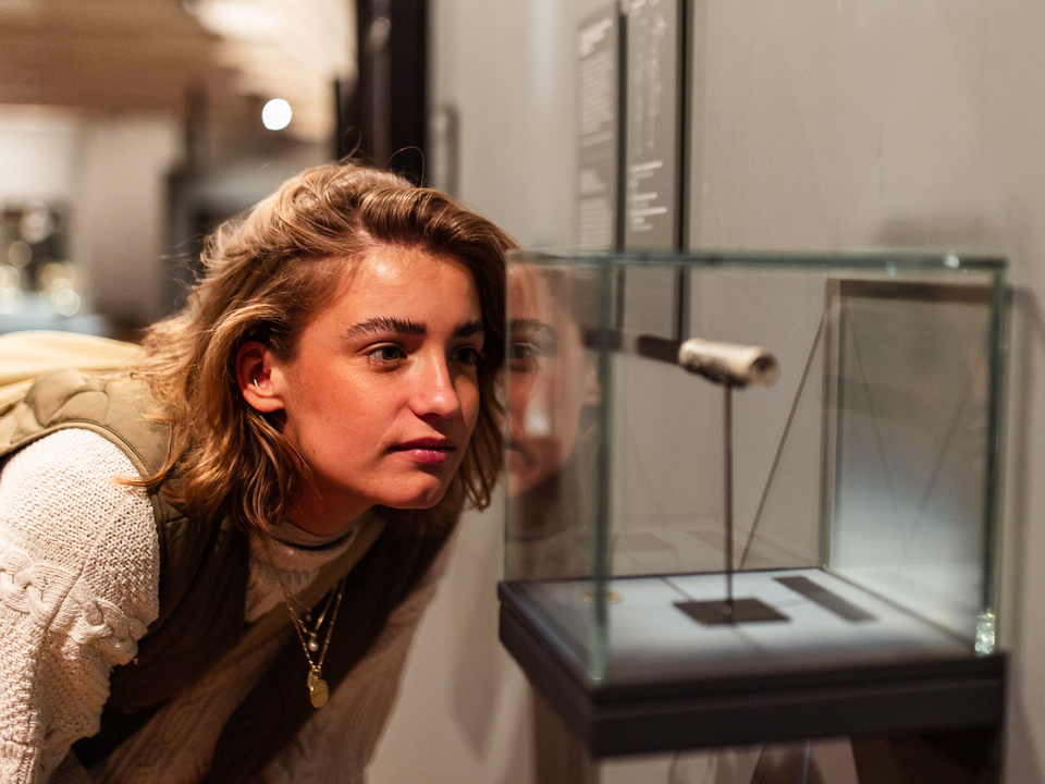 Dame kijkend naar de eerste microscoop gemaakt in Delft