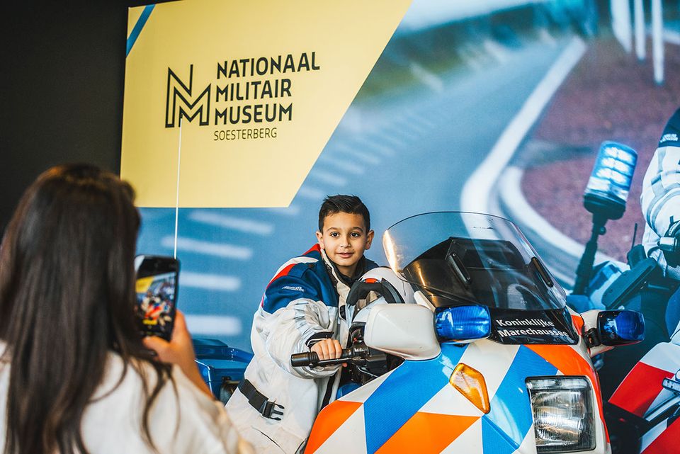 Vrouw die een foto maakt van een kind op een politiemotor