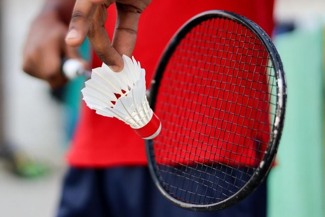 Badminton - close-up van racket met een hand die een shuttle vasthoudt