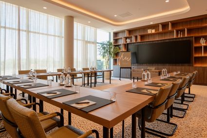 Vergaderlocatie Van der Valk Hotel Woerden in Woerden, provincie Utrecht, ruime moderne vergaderzaal voor zakelijke bijeenkomsten met U-vormige tafelopstelling, presentatiescherm en grote ramen met uitzicht op het Groene Hart.