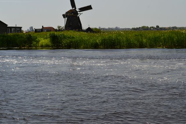 Donkere Waterloosmolen vanuit het water te zien op afstand in Rijpwetering