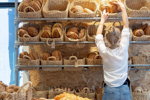 Een medewerker pakt een brood van de plank in de bakkerij.