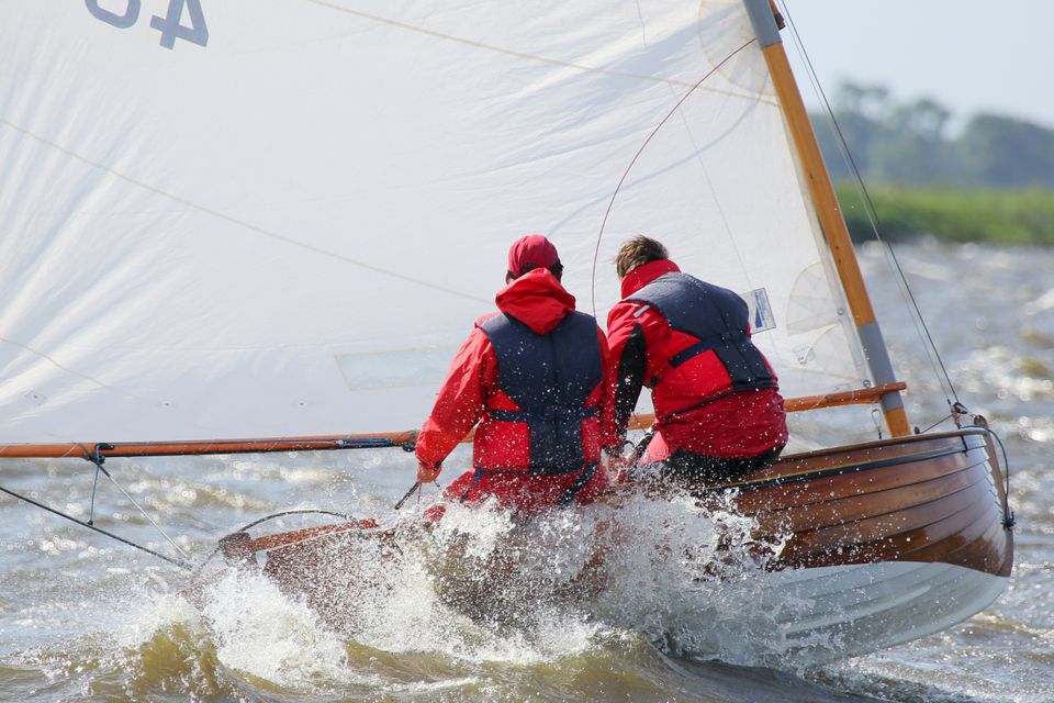 Zeilers met rode jassen en flinke golfslag