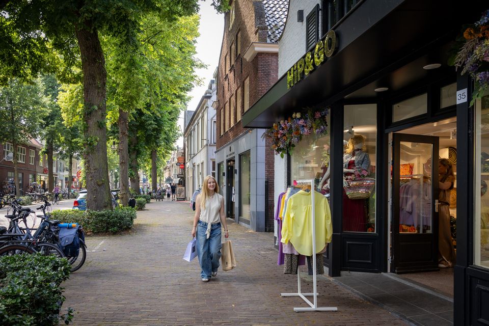 Meisje loopt met twee tassen langs kledingzaak Hip & Go in de Dorpsstraat in Oisterwijk