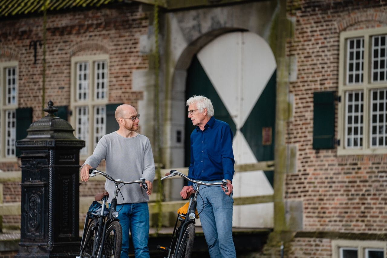 Kasteel Gemert met figuranten die er fiets aan de hand voor staan.