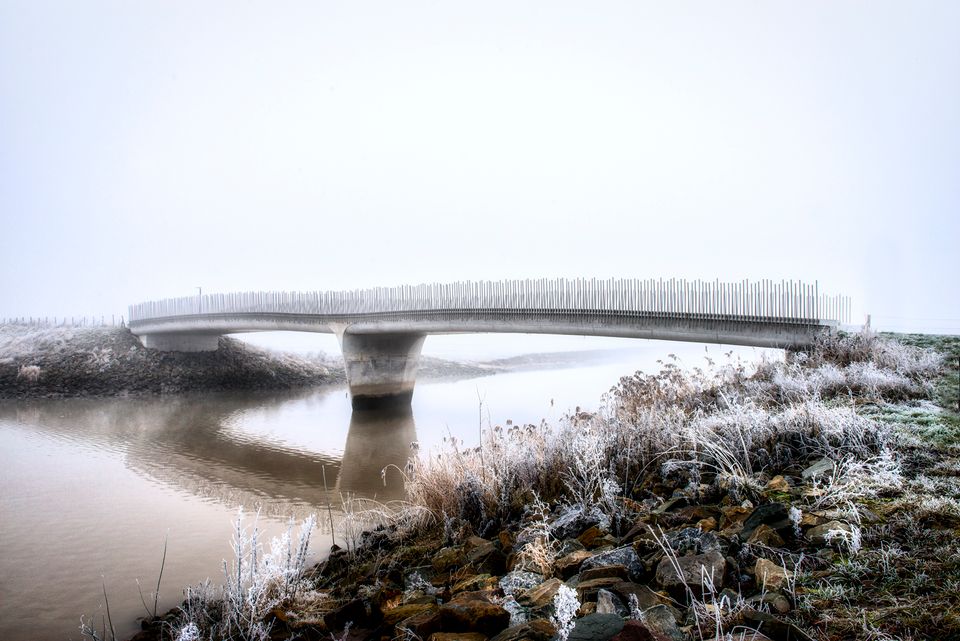 Moderne brug in het buitengebied van Vianen in de winter, met rijp op de oeverplanten en mist boven het stille water in het Groene Hart.