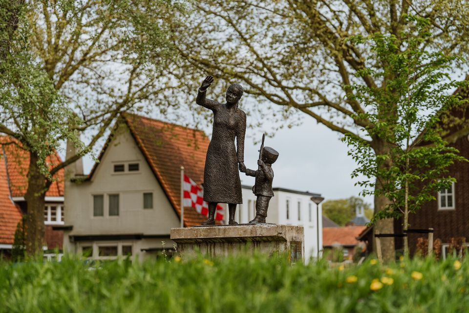 Standbeeld van een moeder en kind die zwaaien.