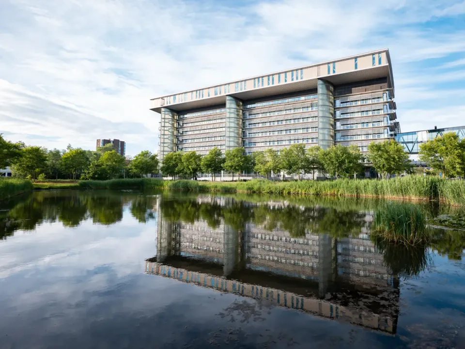 Landscape of Leiden Bio Science Park building, surrounded by trees, reflected in the water.