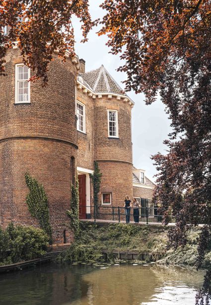 Historisch kasteel Kasteel Montfoort, Montfoort, Groene Hart, bezoekers wandelen langs de ronde bakstenen torens en de gracht van het middeleeuwse kasteel in de historische binnenstad.