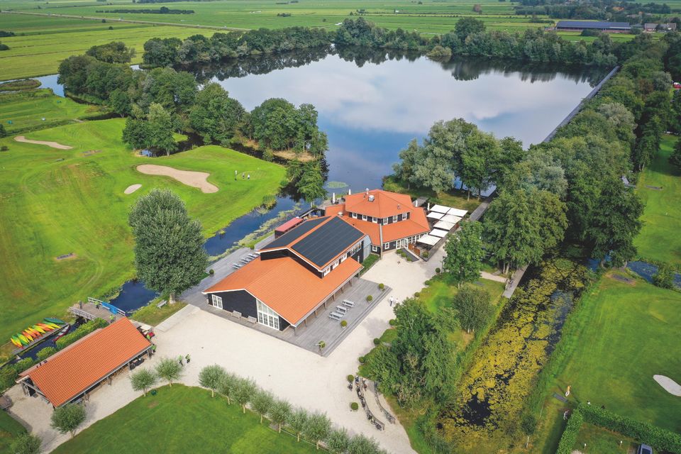 Luchtfoto van Buitenplaats Kameryck te Kamerik aan een plas water met bomen er omheen in een groen gebied met omliggende grasvelden.