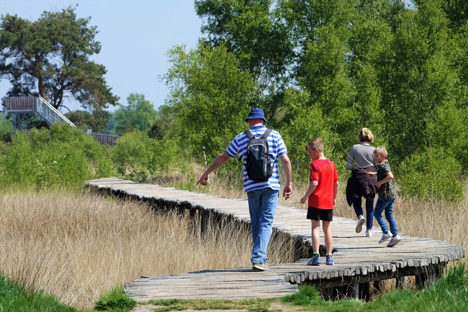 een gezin wandelt over een knuppelbruggetje