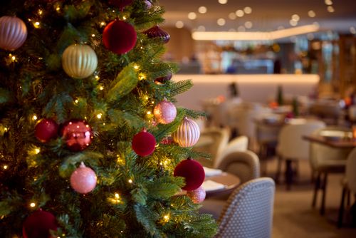 Een kerstboom staat in een sfeervol restaurant
