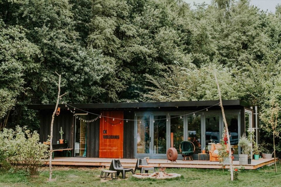 Een vakantiehuisje onder de bomen en een zitje met een vuurplaats.