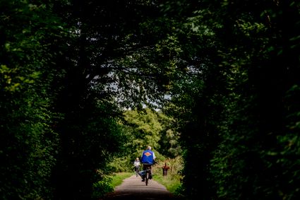Je ziet fietsers tussen de bomen door fietsen