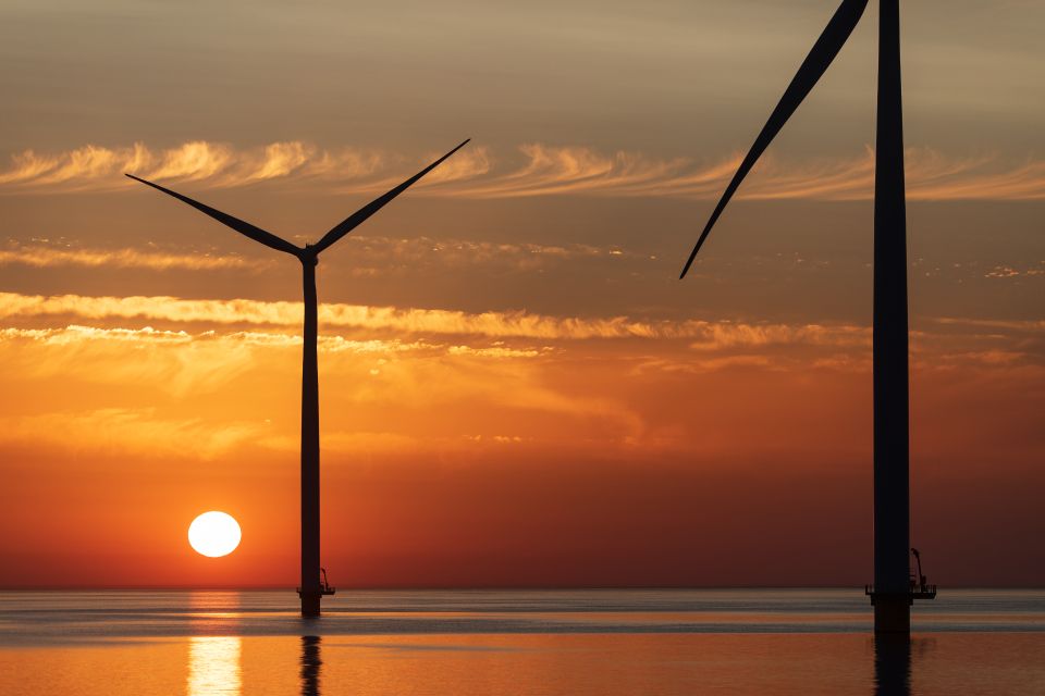 Twee windmolens in het water met de ondergaande zon op de achtergrond in de Noordoostpolder.